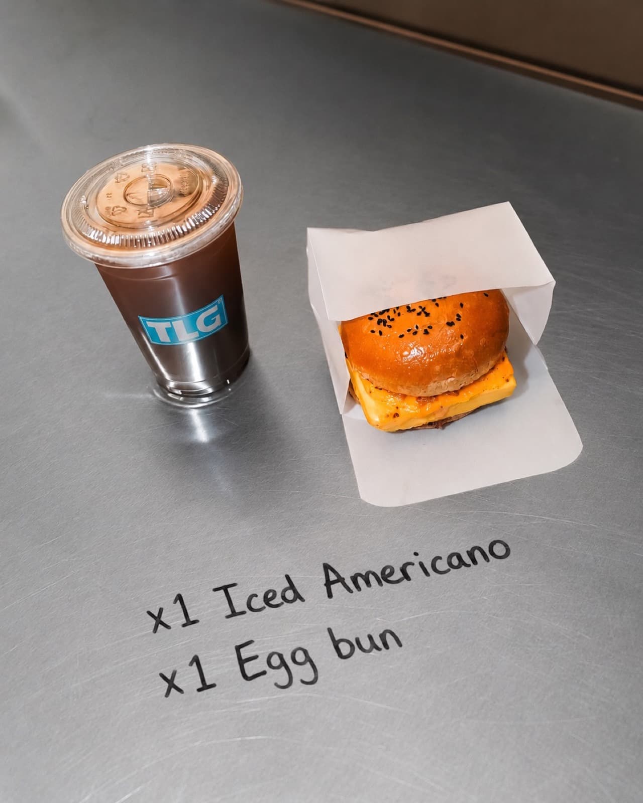 Iced americano and egg bun on the steel counter